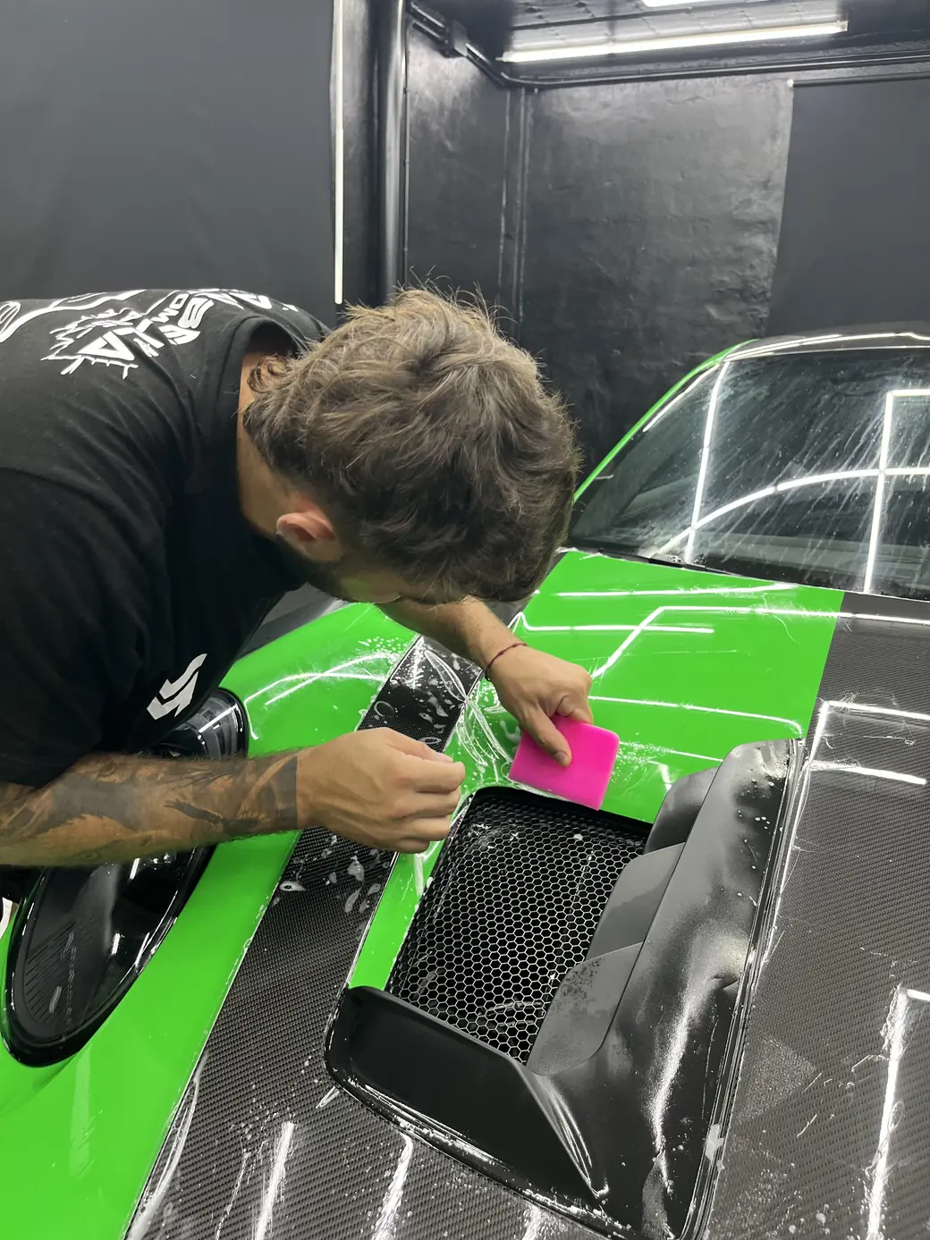 Instalador de Marbella Custom Cars aplicando lámina de protección con espátula sobre el capó de un Porsche